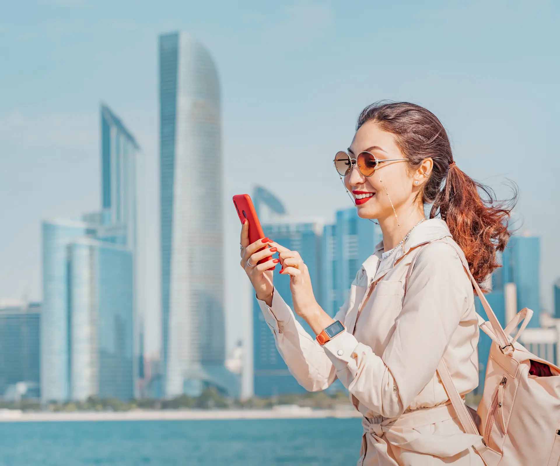 woman using phone in front of skyscrapers